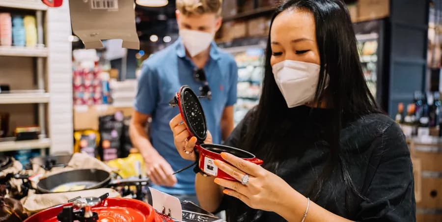 Researcher examining a product in a store while a colleague looks on